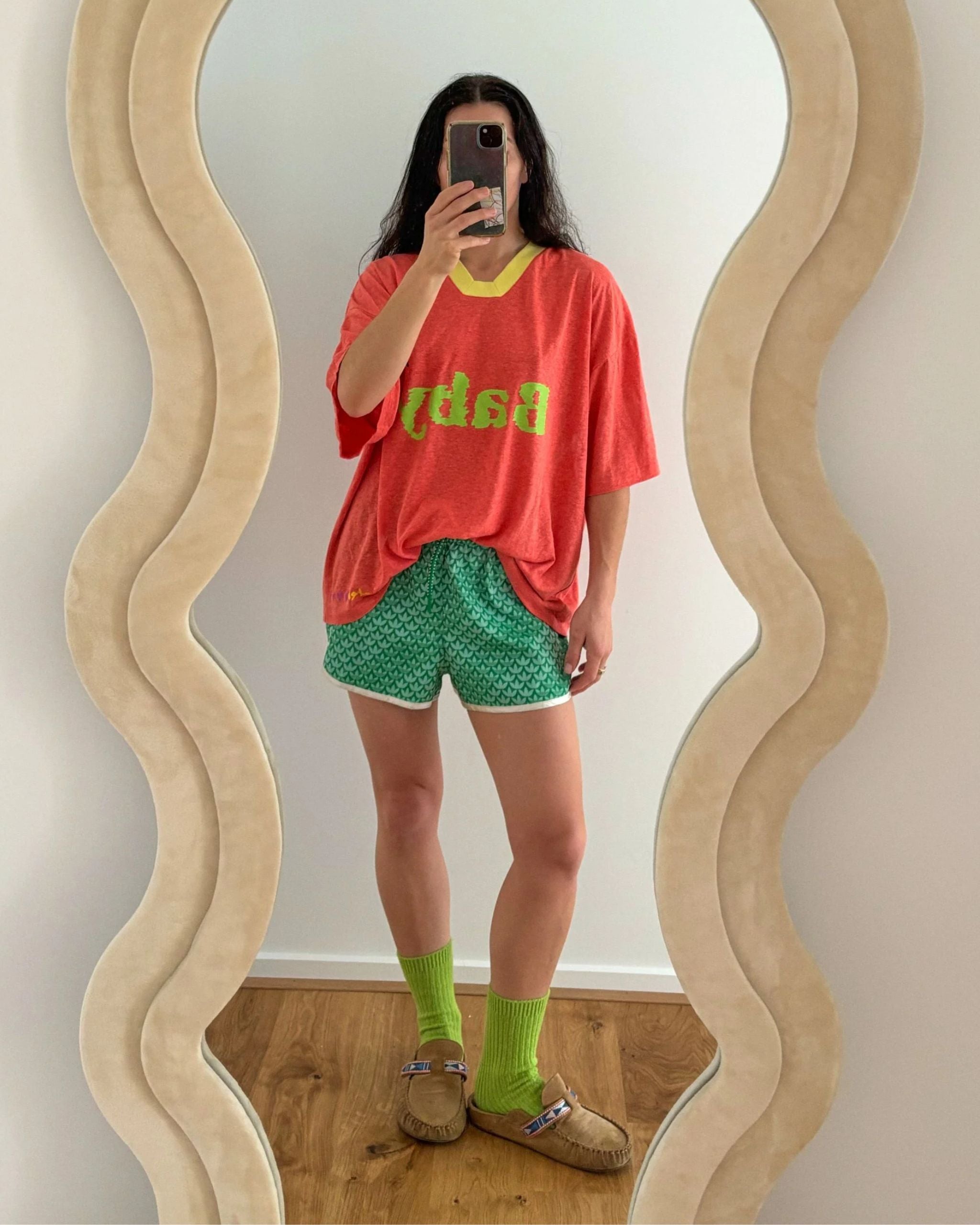 Woman wearing an orange-peach hemp and tencel adult t-shirt with ‘baby sister’ text by Yolky Club