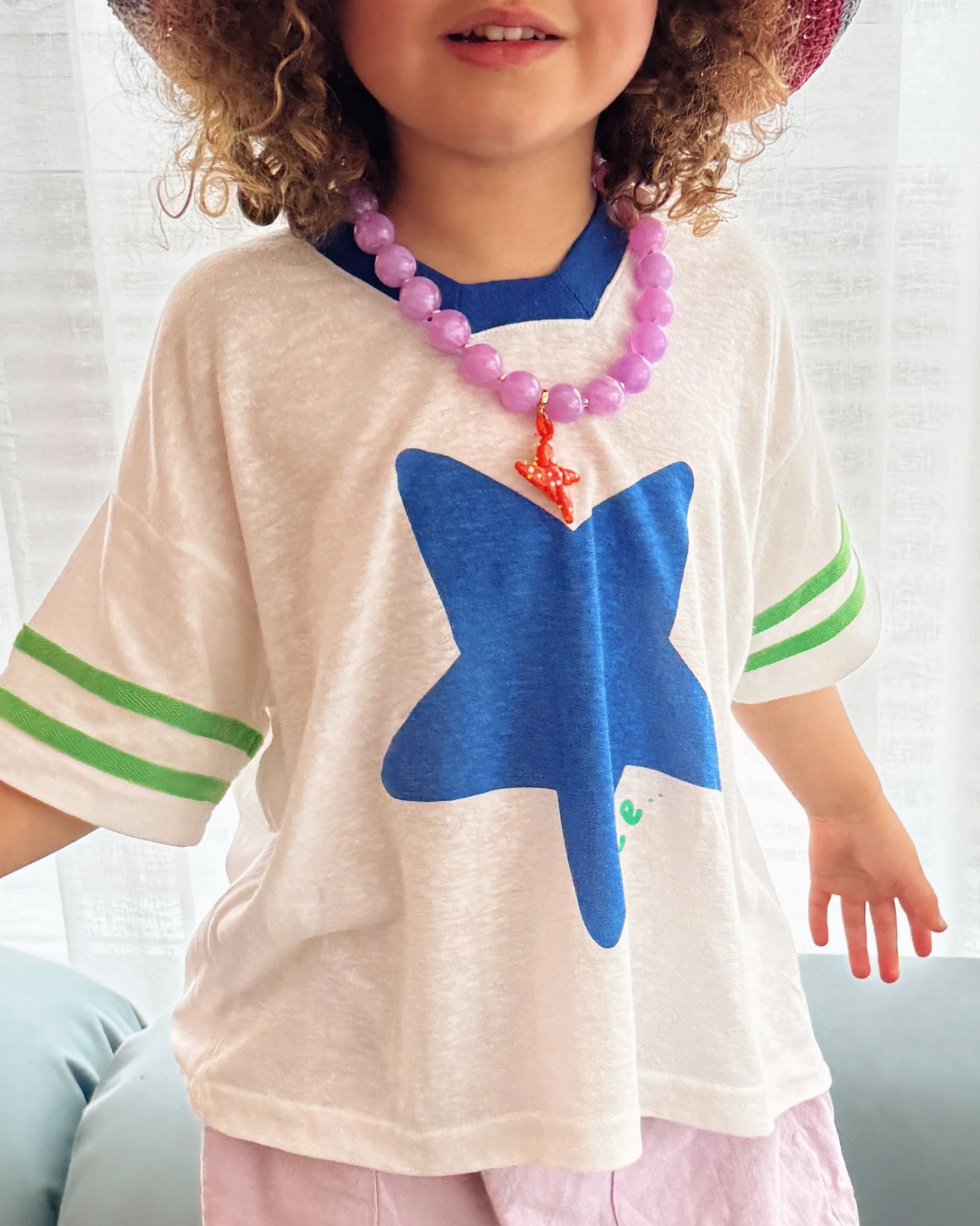 Close-up of white hemp and tencel kids t-shirt with blue star and green textured stripes on the sleeves by Yolky Club