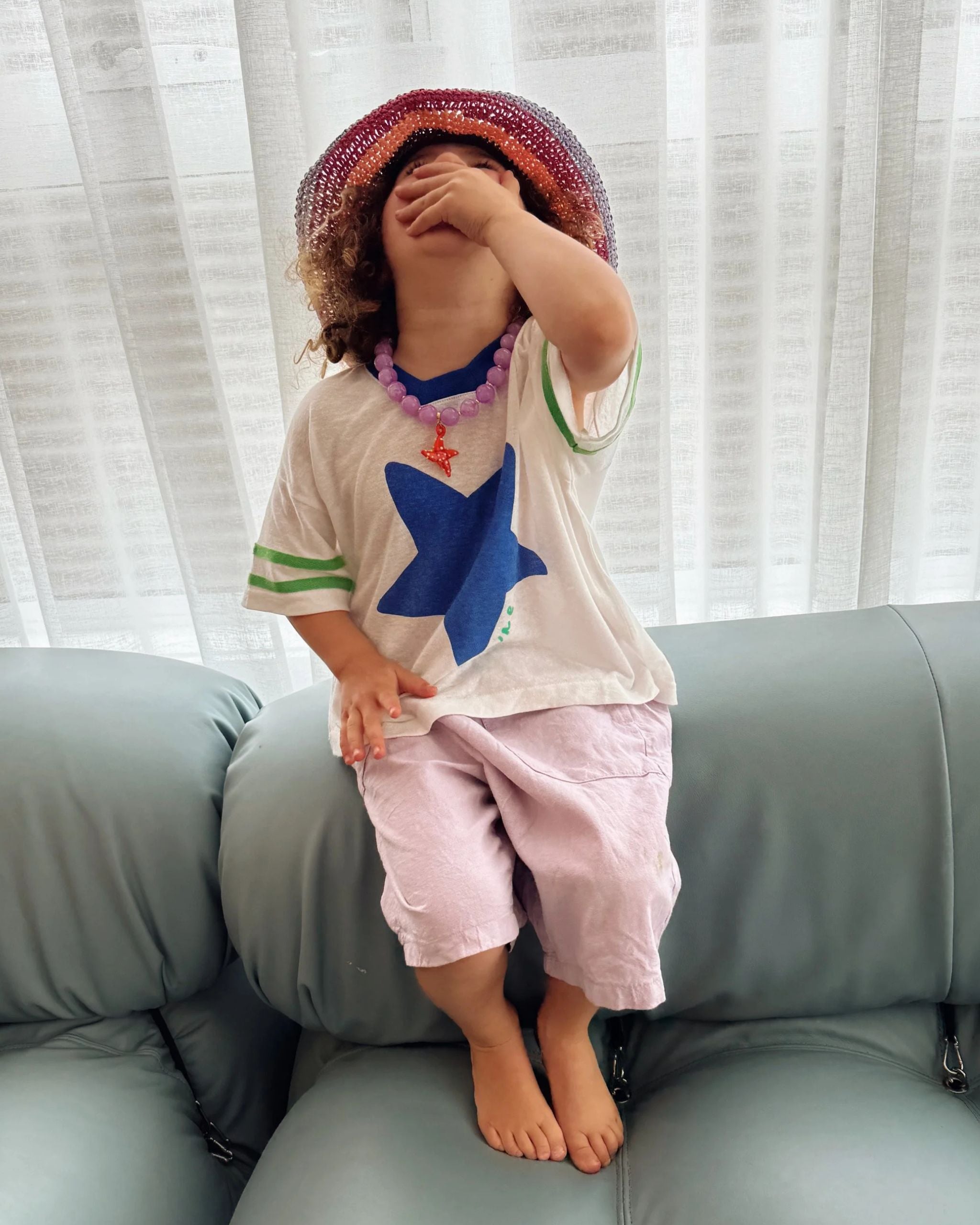 Child wearing a white hemp and tencel kids t-shirt with a large blue star on the front and green textured stripes on the sleeves by Yolky Club