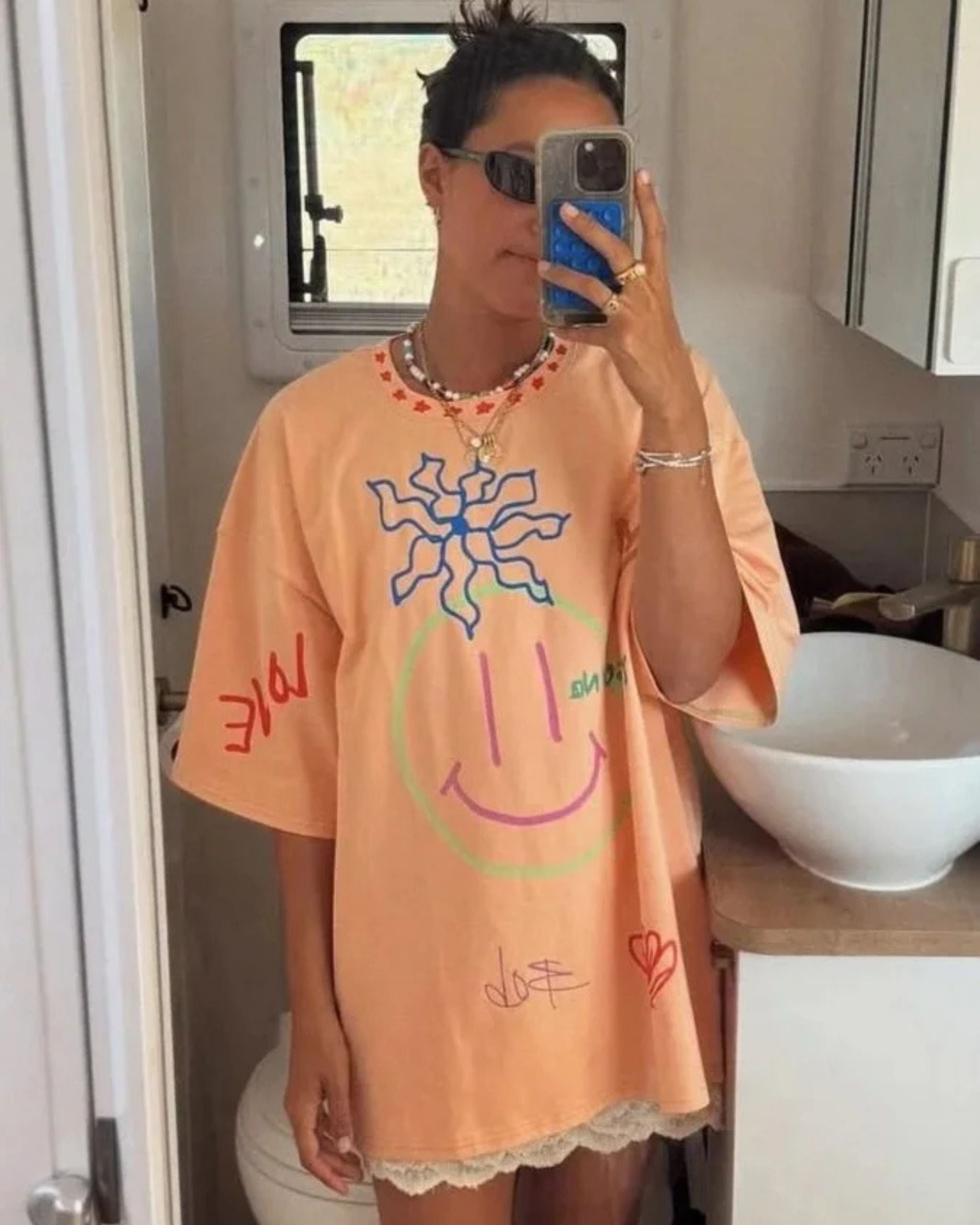 Woman wearing an orange organic cotton adult t-shirt with hand-drawn illustrations by Yolky Club